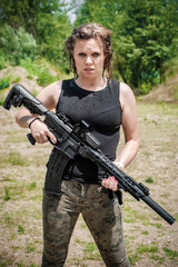 Wet female army soldier hold rifle machine gun. Woman with weapon. Firearm outdoor shooting range