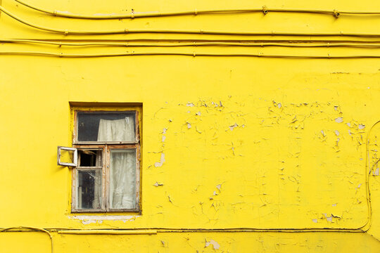 Cracked yellow wall with a wooden window. Copy space