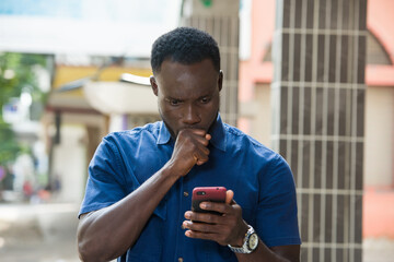 young man using a mobile phone, looks shocked