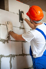 Mason aligning aerated autoclaved concrete block of constructed house wall