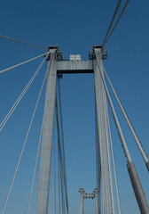 Supports of a suspension bridge with cables against the blue sky.