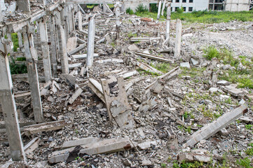 Top view of a pile of gray concrete rubble against the remains of a large destroyed building. Background