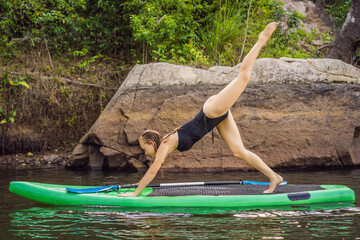 Sporty woman in yoga position on paddleboard, doing yoga on sup board, exercise for flexibility and stretching of muscles