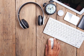 Hand business man use computer on office desk table with computer,wireless earphone,alarm clock and business objects, Top view with copy space for your text and business background.