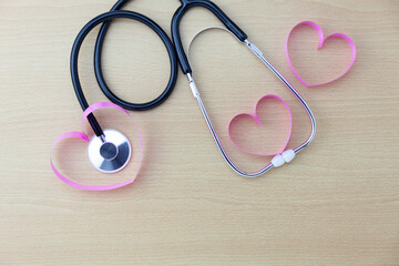 Stethoscope with heart ribbon on wooden table background copy space for your text.