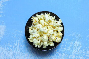      popcorn in black bowl, decorative blue background     