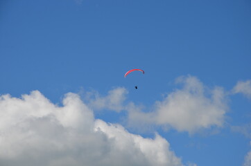 Paraglider pilot in Talloires-Montmin area near Annecy in Upper Savoy (Haute Savoie), France, blue sky background with clouds, a sunny day in summer