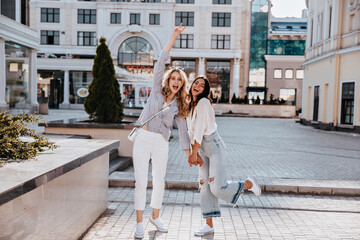 Full-length photo of dark-haired lady in vintage jeans standing on one leg. Positive female friends...