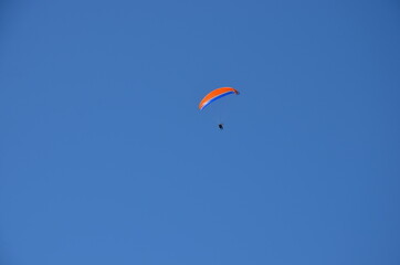 Paraglider pilot in Talloires-Montmin area near Annecy in Upper Savoy (Haute Savoie), France, blue sky background with clouds, a sunny day in summer
