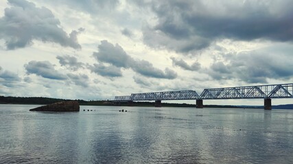 railway bridge over the river against the backdrop of a gloomy cloudy sky