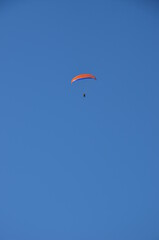 Paraglider pilot in Talloires-Montmin area near Annecy in Upper Savoy (Haute Savoie), France, blue sky background with clouds, a sunny day in summer