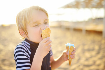 Preschooler boy eating ice cream on hot summer day on beach during family holiday.Gelato is loved delicacy for kids. Sweets are unhealthy food for children. Diabetes, obesity