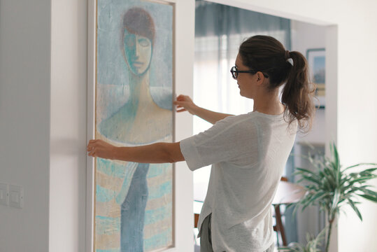 Woman hanging a painting at home
