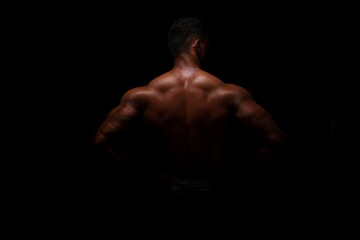 Obraz na płótnie Canvas Silhouette of young athlete bodybuilder man on black