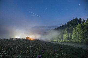 the fog descending on the river is mysteriously illuminated by the lanterns of tourists resting on...