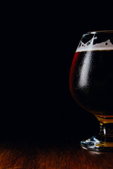 A glass of brown ale  on a wooden table and dark background