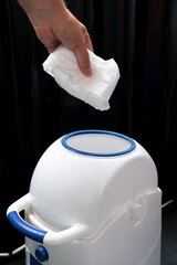 We throw the baby diaper into the waste bin. Rubbish in the trash can.