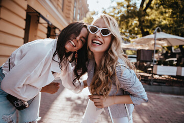 Glad brunette woman chilling with best friend. Winsome girl in sunglasses enjoying weekend with...