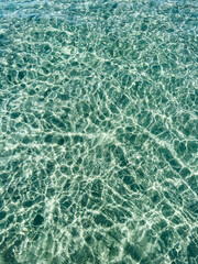 Small waves on the transparent clear water of the sea. Sun glare on the surface of the water in sunny weather
