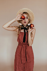 Shocked girl in vintage attire posing with peach. Indoor shot of amazed elegant woman with long blonde hair.