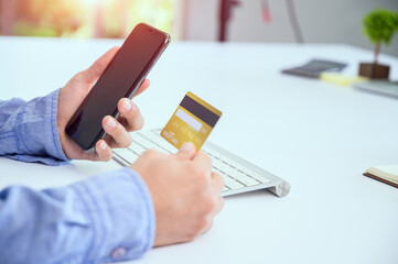 A man using a smart phone and holding a panoramic banner of a credit card Young businessmen or entrepreneurs who work at the office Online shopping