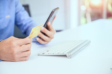 Fototapeta premium A man using a smart phone and holding a panoramic banner of a credit card Young businessmen or entrepreneurs who work at the office Online shopping