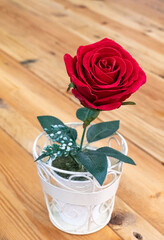 Artificial flower of the red rose in the white vase.