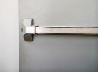 Close-up of the rusty metal handle on the fire exit door.