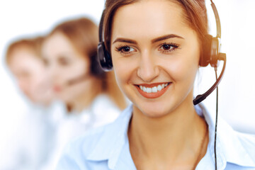 Call center operators. Focus on beautiful business woman using headset in sunny office