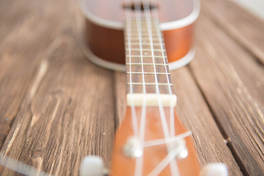 Photo depicts musical instrument ukulele guitar on wooden table