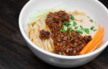 Sichuan Spicy Noodle with garlic chili oil and minced pork, serving on white bowl. Traditional food of Sichuan province. Chinese food concept.