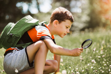 Young boy exploring nature in a meadow with a magnifying glass
