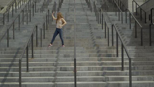 extra long shot. Young girl contemporary dancer dancing on marble steps. straight lines video. 4K