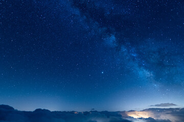 Starry blue sky above a sea of clouds at night. Night photography of long exposure landscapes with...