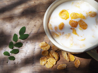 Cornflakes in a white cup on a shabby wooden floor Space for text