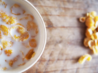 Cornflakes in a white cup on a shabby wooden floor Space for text