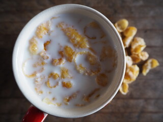 Cornflakes in a white cup on a shabby wooden floor Space for text
