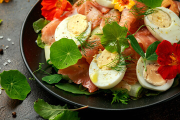 Smoked salmon and cucumber salad with nasturtium leaves and edible flowers. healthy food