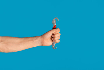 Unrecognizable man holding universal spanner over blue background, blank space