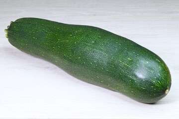 isolated dark green zucchinini on a light wooden surface