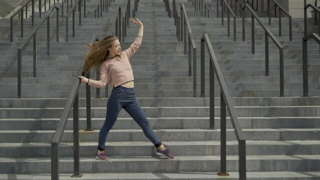 long shot. Young girl contemporary dancer dancing on marble steps in a pink sweater. straight lines video. 4K