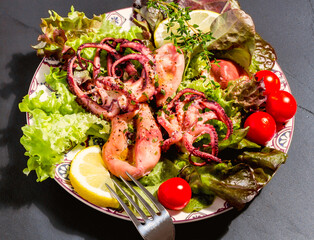 Octopus on blue plate with salad and lemon