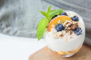 Healthy blueberry, peach and walnut parfait in a glass on a dark background