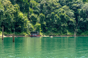 Kenyir, Malaysia - July 23, 2020: Houseboat crusing through the lake with mountain view at Kenyir Lake. Tasik Kenyir is a man made lake.