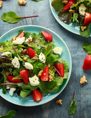 Goats cheese and strawberry summer salad served with nigella and sesame seeds drizzled with runny honey