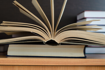 open book in the shape of a fan lies on the table against the background of other books