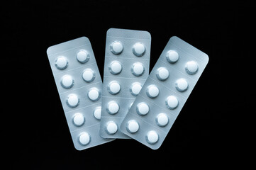 Blister pack full of white pills isolated on a black background. Full pills package. Pharmaceutical blister pack. Pack of tablets.