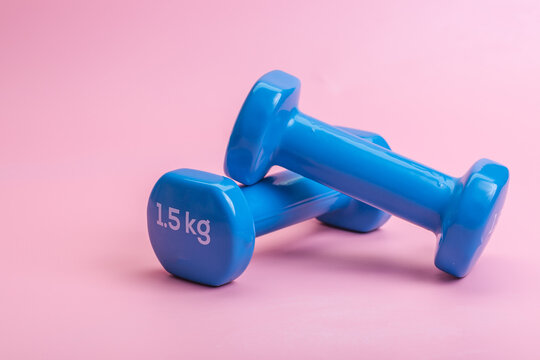A pair of blue dumbbells on a pink background