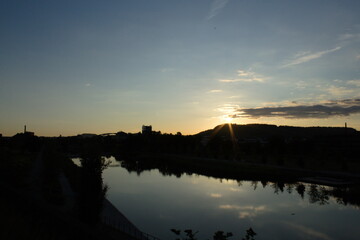 Sonnenaufgang und Sonne mit Sonnenstarahlen, Silhouette und Spiegelung im See