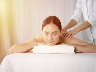 Obraz na płótnie Canvas Pretty brunette woman enjoying procedure of back massage in sunny spa salon. Beauty concept